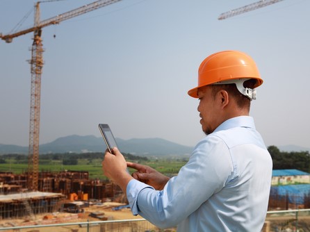 Man holding smartphone on construction site