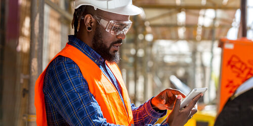 man using tablet on construction site for safety