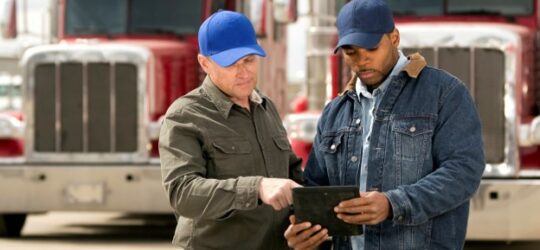 two truck drivers with tablet performing a pre-trip inspection