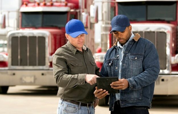 two truck drivers with tablet performing a pre-trip inspection