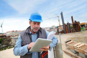 man on construction site looking at digital tablet device
