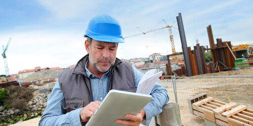 man on construction site looking at digital tablet device