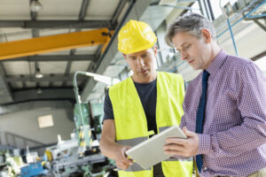 two men on a construction site looking at a tablet device