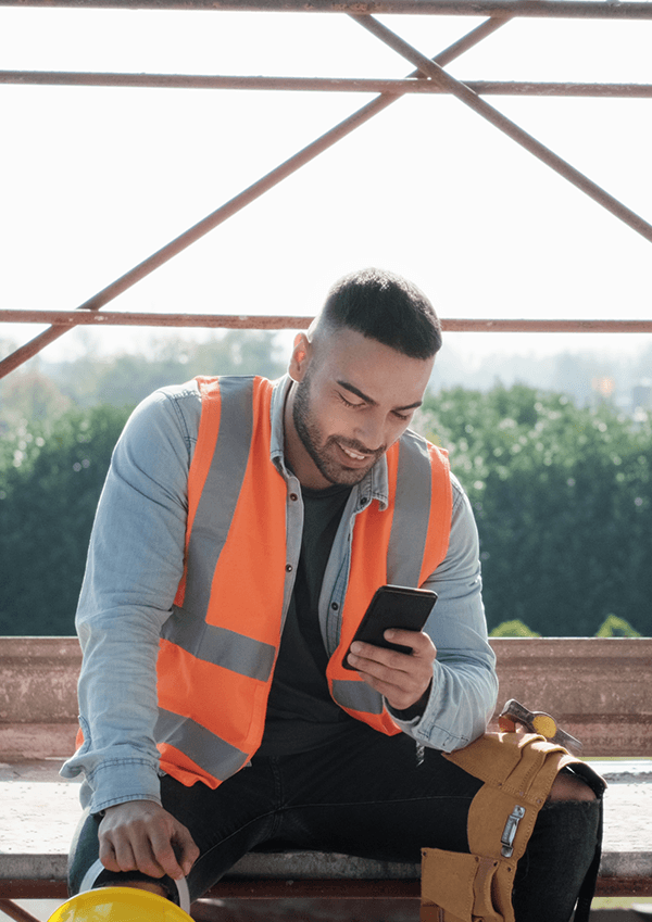 A construction worker checking phone for work updates.