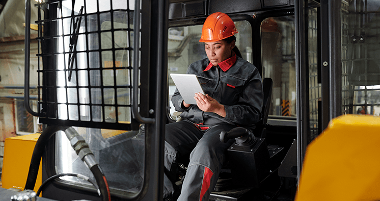 Woman looking at tablet inside a large vehicle machine.