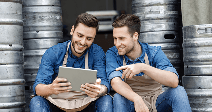 Image of two men in front of kegs on tablet.